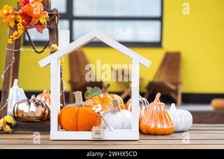 Decorazioni autunnali su portico di casa gialla all'esterno di zucca, lanterna, ghirlande e figura di casa e chiave. Festa di Halloween, autunno Foto Stock