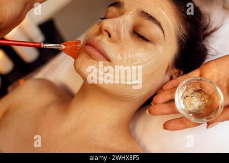 Il maestro di bellezza applica una maschera ringiovanente al viso dei clienti Foto Stock