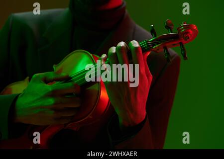 Vibrant Closeup of Man Playing Violin con sfondo illuminante a luce verde e rossa Foto Stock