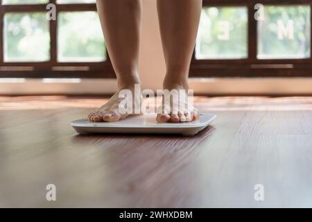 Dieta grassa e piedini graduati posizionati su bilance elettroniche per il controllo del peso. Strumento di misurazione in chilogrammi per il controllo della dieta Foto Stock