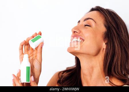 Bella donna caucasica ridendo che tiene in mano un tubo bianco con stiker verdi in mano. Foto Stock