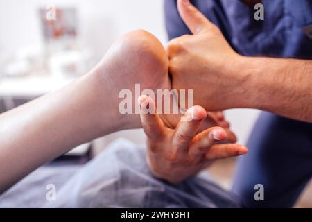 Primo piano del piede femminile con un massaggio delicato. La massaggiatrice tiene la gamba della donna nelle sue mani. Un giovane cliente mente e ama rilassarsi con un professionista Foto Stock