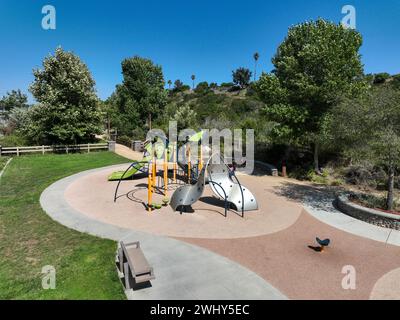 Colorato parco giochi per bambini attività nel parco pubblico circondato da verdi alberi Foto Stock