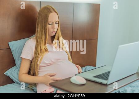 La donna incinta stanca di lavorare da casa, affronta le sfide dell'equilibrio tra attività professionali e richieste di gravidanza Foto Stock