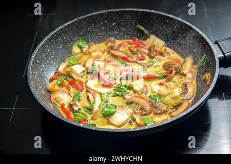 Curry tailandese vegetale in una padella, ingredienti come peperone rosso, funghi, pak choi, condito con zenzero, curcuma e o Foto Stock