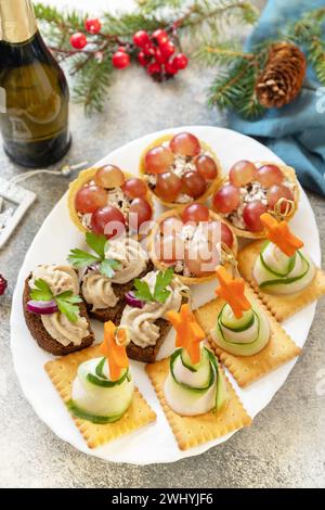 Gli antipasti creativi preparano il natale. Alberi di Natale di prosciutto, cetriolo, formaggio e stella di carota su cracker, tartine con chicke Foto Stock