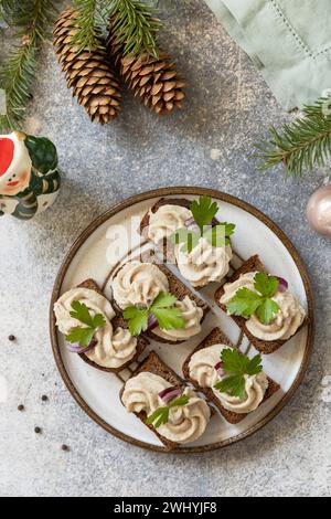 Aperitivo creativo di natale. Pate cremosi panini di aringhe su pane di segale sul tavolo delle feste. Vista dall'alto. Foto Stock