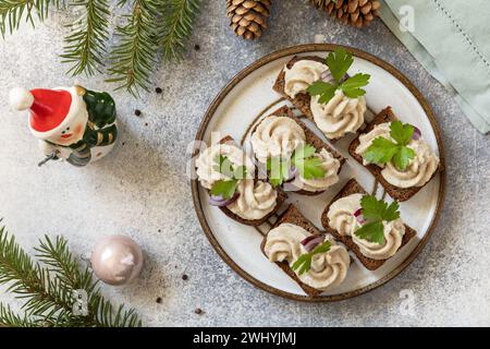 Aperitivo creativo di natale. Pate cremosi panini di aringhe su pane di segale sul tavolo delle feste. Vista dall'alto. Foto Stock