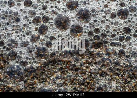 Macrofotografia, bolle di mare, grani di sabbia, vista ravvicinata, texture costiere, dettagli bollicine, bellezza oceanica Foto Stock