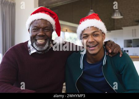 Felice padre e figlio afroamericano nei cappelli di natale che hanno videochiamata, sorridendo Foto Stock