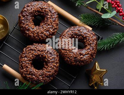 Ciambelle al cioccolato cosparse di noci schiacciate su un tavolo nero Foto Stock