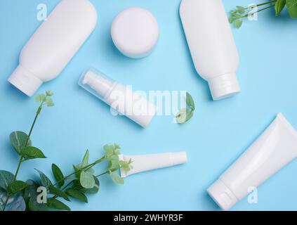 Tubi di plastica bianca, vasetti e contenitori per prodotti cosmetici su sfondo blu, pubblicità e branding dei prodotti Foto Stock