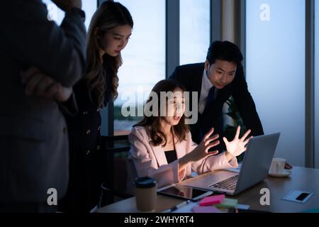 Gruppo di intermediari di borsa internazionali che lavorano attivamente di notte in carica, Una giovane donna lavora sodo per presentare un cl Foto Stock