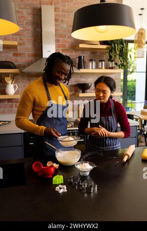 Allegri coppie che preparano biscotti natalizi mescolando l'impasto in cucina, spazio per copiare Foto Stock