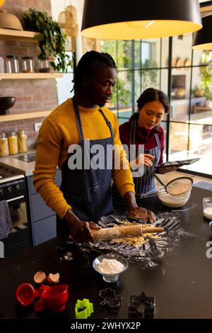 Allegri coppie che preparano i biscotti di natale usando un tablet in cucina Foto Stock