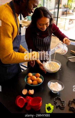 Allegri coppie che preparano biscotti natalizi mescolando l'impasto in cucina, spazio per copiare Foto Stock