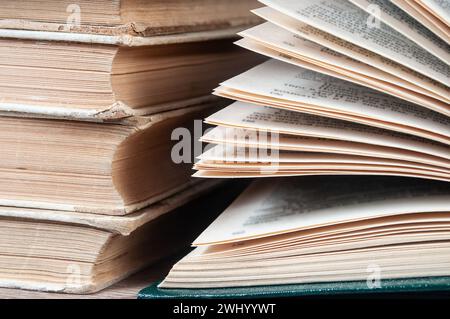 Una pila di vecchi libri e un libro pieghevole in primo piano Foto Stock