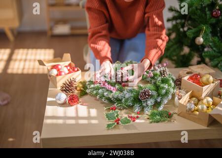 Donna che produce ghirlande di vigna decorazione di ghirlanda di Natale con fiori di verde invernale fatti a mano che creano wrea di Natale Foto Stock