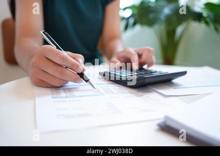 Imprenditrice contabile che analizza i grafici di investimento fattura e preme i pulsanti di calcolo sui documenti. Contabilità Foto Stock