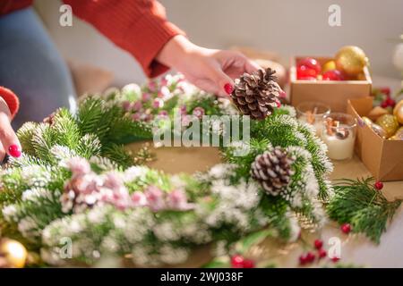 Donna che produce ghirlande di vigna decorazione di ghirlanda di Natale con fiori di verde invernale fatti a mano che creano wrea di Natale Foto Stock