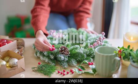 Donna che produce ghirlande di vigna decorazione di ghirlanda di Natale con fiori di verde invernale fatti a mano che creano wrea di Natale Foto Stock