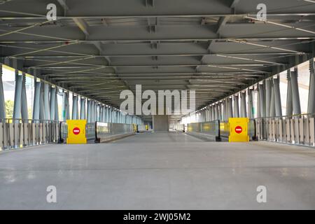Long Bridge Corridor, recinzione gialla con un cartello in mattoni, è vietato il passaggio su un viaggiatore, su un passaggio pedonale sopraelevato all'aeroporto, sulla ferrovia Foto Stock