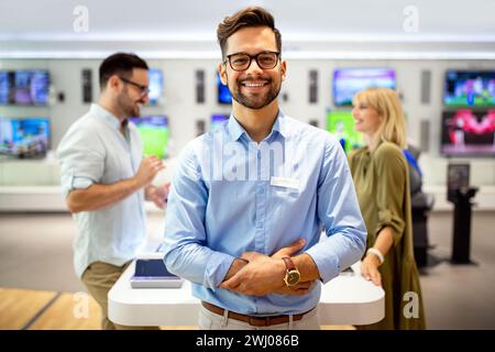 Il consulente di vendita consiglia le persone che scelgono nuovi dispositivi digitali nei punti vendita. Consulenza professionale Foto Stock