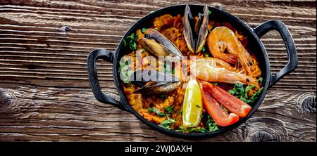 Paella di pesce servita in una padella di ghisa. Foto Stock