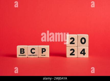 L'abbreviazione BCP business continuity plan per l'anno 2024 su cubi di legno con sfondo rosso. Foto Stock