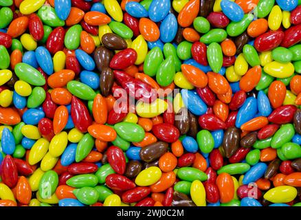 Dolci dolci assortiti glassati multicolore, con nocciole, semi o centro di cioccolato, fondo di pasticceria astratto Foto Stock