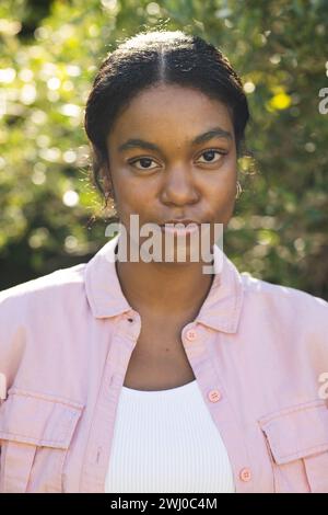 La giovane donna birazziale sta all'aperto, inondata dalla luce del sole Foto Stock