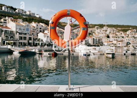 Lifebuoy su un piedistallo con chiavistello si trova su un molo di Lustica Bay. Montenegro Foto Stock