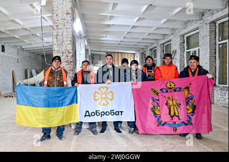 ZAPORIZHZHIA, UCRAINA - 9 FEBBRAIO 2024 - Coordinatore della divisione Zaporizhzhia della ONG Dobrobat Andrii Razin (3° L) posa per una foto con i volontari di Dobrobat che riparano l'Accademia Nazionale Khortytsia danneggiata dai bombardamenti russi, Zaporizhzhia, Ucraina sudorientale. Foto Stock