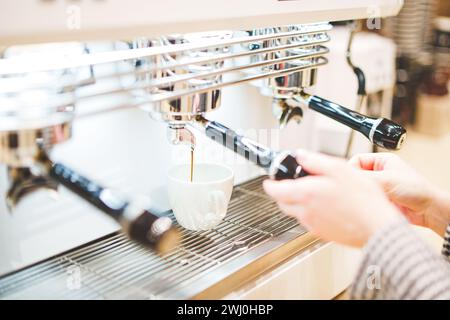 Primo piano del caffè erogato dalla macchina per il caffè. Preparazione professionale del caffè. Foto di alta qualità Foto Stock