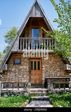 Sentiero lastricato verso una casa triangolare in pietra in un giardino verde Foto Stock