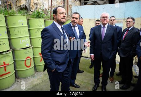 12 febbraio 2024, Cipro, Nikosia: Il presidente tedesco Frank-Walter Steinmeier (3° da sinistra) e Nikos Christodoulides (a sinistra), presidente della Repubblica di Cipro, stanno insieme a Constantinos Yiorkadjis (centro), sindaco di Nicosia, alla "linea verde". La "linea verde” è la zona cuscinetto demilitarizzata monitorata dalle Nazioni Unite (ONU) tra Cipro del Nord occupata dalla Turchia e la Repubblica di Cipro. Il presidente federale Steinmeier è il primo presidente tedesco a visitare il paese nel Mediterraneo orientale, 20 anni dopo l'adesione del paese all'Unione europea (UE) e 50 anni Foto Stock