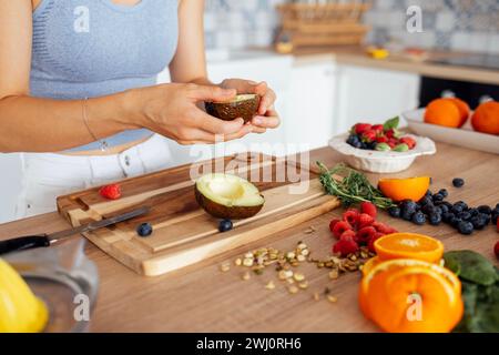 Una bella donna asiatica sorride e cucina la colazione in cucina. Una giovane e affascinante donna coreana ride e taglia la vegetale Foto Stock