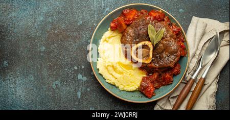 Piatto tradizionale italiano Ossobuco, tutto milanese, con carne di vitello tagliata con salsa di pomodoro vegetale, servito con polenta di mais Foto Stock