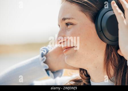 Beach Beats: Il turista illuminato dal sole gode di musica in riva al mare Foto Stock