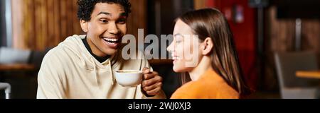 Un uomo di contenuti sorseggia il suo caffè caldo mentre condivide un sorriso con la sua elegante ragazza, il banner Foto Stock