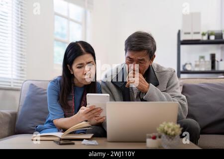 Grave stress asiatico anziani coppia preoccupata per la fattura discutere non pagato debito bancario pagamento carta preoccupazione per problema di denaro Foto Stock