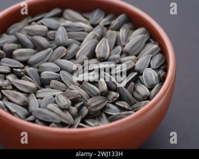 Semi di girasole in una ciotola su sfondo nero. Primo piano. Foto Stock