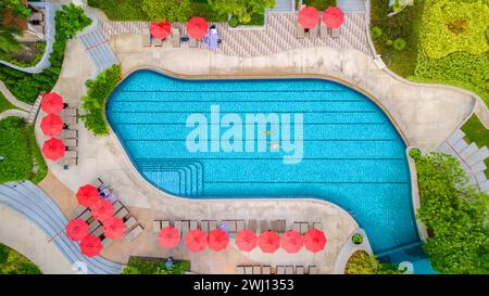 Vista dai droni dall'alto su una coppia che nuota in una piscina a sfioro durante una vacanza di lusso in Thailandia Foto Stock