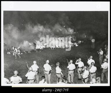 TULSA RACE RIOT (31 maggio e 1 giugno 1921): Polizia disperde marcheggiatori con Tear gas . Fotografia di afroamericani che stanno cercando di fuggire dalle loro tende che sono stati appena attaccati con gas lacrimogeni da soldati che si schierano in piedi con maschere antigas e pistole in primo piano. Foto Stock