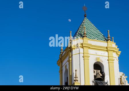 primo piano di un campanile di chiesa con un cielo blu e la luna sullo sfondo Foto Stock