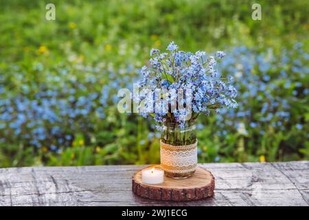 Bouquet di fiori selvatici in fiore blu Myosotis, noto anche come Forget me Not o erbe scorpioni in un vaso muratore decorato. Bellissimo ancora floreale d'epoca. Foto Stock