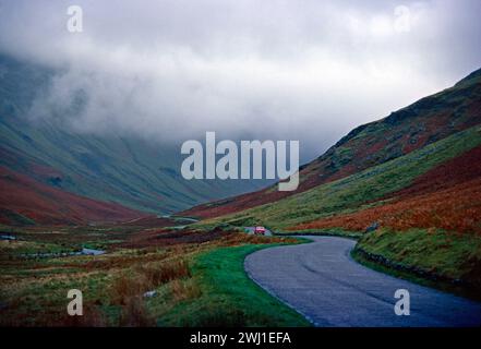 Inghilterra. Cumbria. Strada che attraversa la valle. Nuvola bassa. Foto Stock