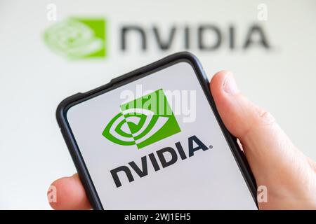 Tenere a mano il telefono cellulare con il logo Nvidia dello sviluppatore di processori grafici schermo del computer Foto Stock