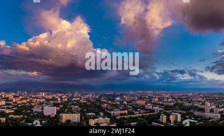 Serata estiva con un colorato tramonto sulla città di Almaty. Grandi e soffici nuvole sono illuminate di rosa dal sole che tramonta. Kazakistan Foto Stock