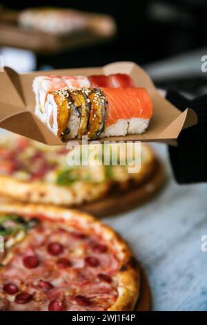 set di sushi su scatola da imballaggio in mano su sfondo per pizza. cibo di strada Foto Stock